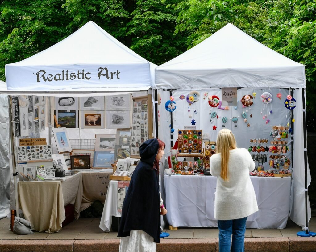 Two women browsing art and crafts at an outdoor market
